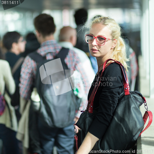 Image of Young blond caucsian woman waiting in line.