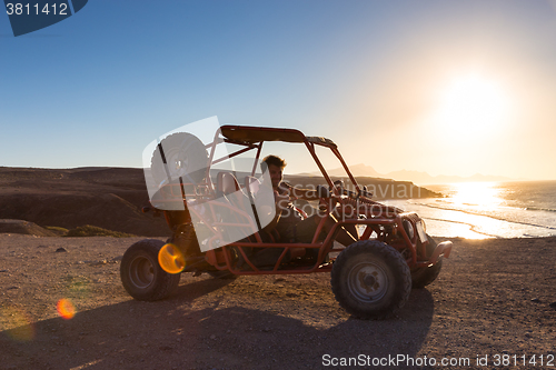Image of Man driving quadbike in sunset.