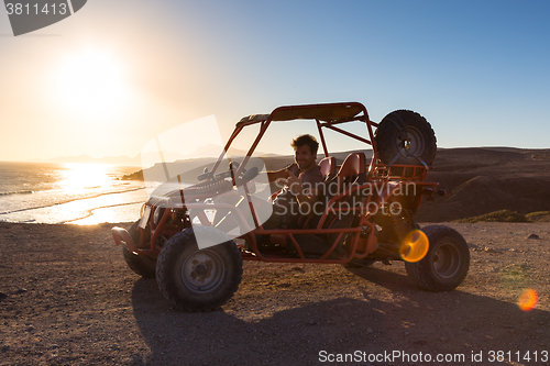 Image of Man driving quadbike in sunset.