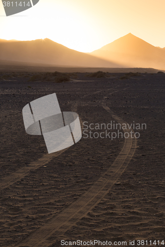 Image of Wheel tracks in sand in dramatic landscape.