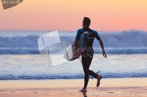 Image of Silhouette of surfer on beach with surfboard.