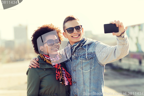 Image of happy teenage friends in shades taking selfie
