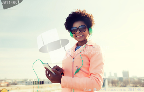 Image of happy young woman with smartphone and headphones