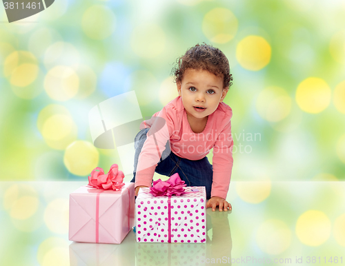 Image of baby girl with birthday presents and confetti