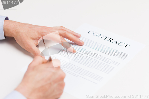 Image of close up of male hands signing contract document