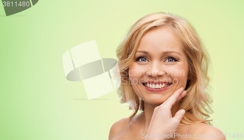 Image of smiling woman with bare shoulders touching face