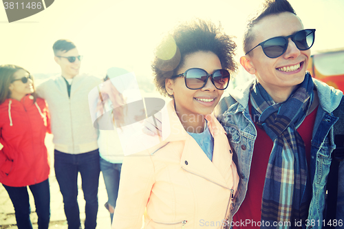 Image of happy teenage friends in shades hugging on street