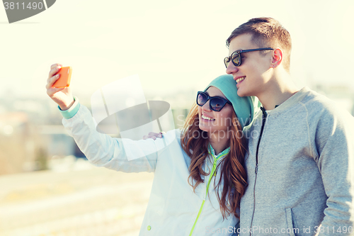 Image of smiling couple with smartphone taking selfie