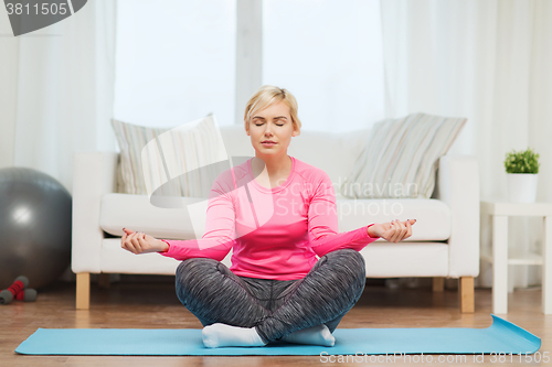 Image of happy woman stretching leg on mat at home