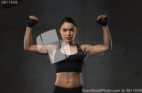 Image of young woman flexing muscles in gym