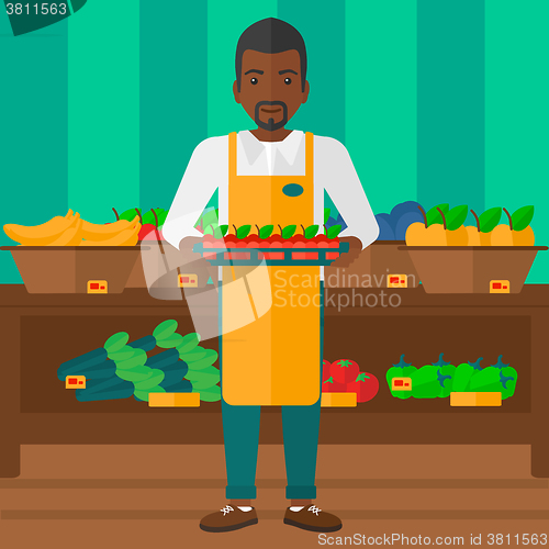 Image of Supermarket worker with box full of apples.