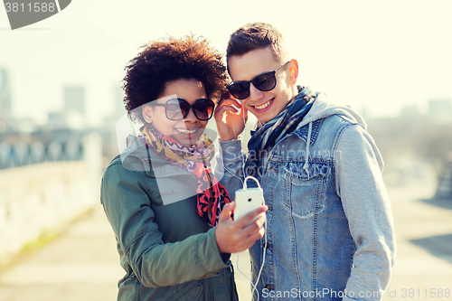 Image of smiling couple with smartphone and earphones