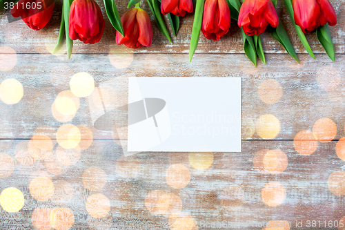 Image of close up of red tulips and blank paper or letter