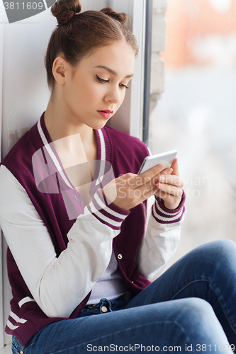 Image of sad pretty teenage girl with smartphone texting