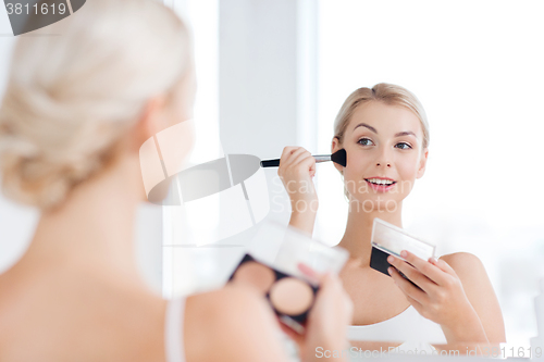 Image of woman with makeup brush and foundation at bathroom