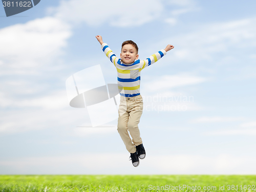 Image of happy little boy jumping over blue sky and grass