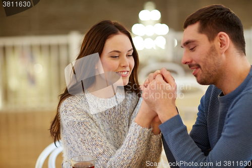 Image of happy couple holding hands at restaurant or cafe