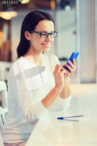 Image of smiling woman with smartphone at cafe