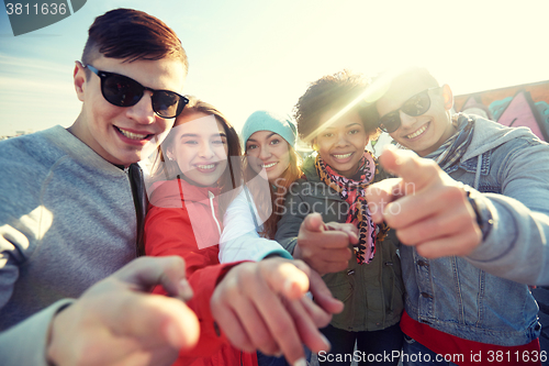 Image of happy teenage friends pointing fingers on street