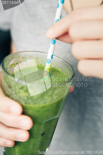 Image of woman holding a glass of green smoothie