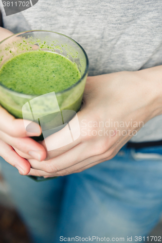 Image of woman holding a glass of green smoothie