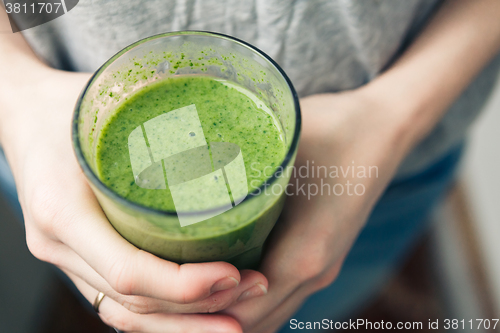 Image of woman holding a glass of green smoothie