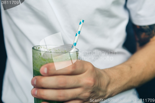 Image of Man holding a glass of green smoothie