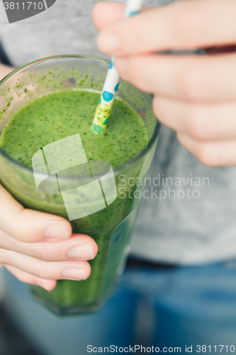 Image of woman holding a glass of green smoothie