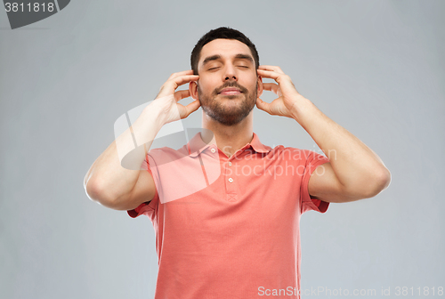 Image of happy man listening to music over gray background