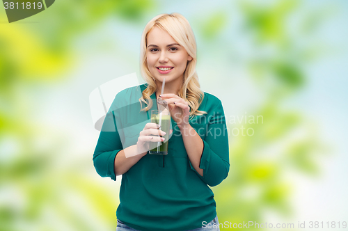 Image of smiling woman drinking vegetable juice or smoothie