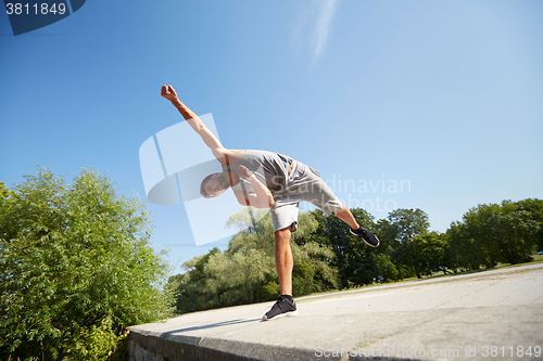 Image of sporty young man jumping in summer park