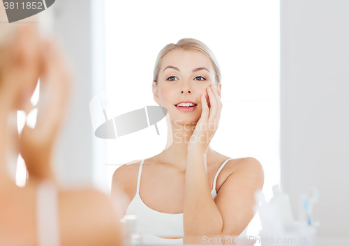 Image of happy young woman looking to mirror at bathroom