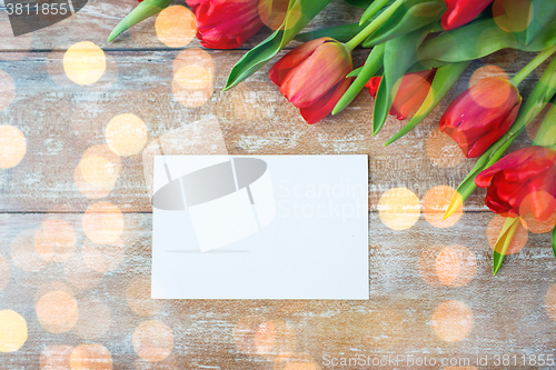 Image of close up of red tulips and blank paper or letter