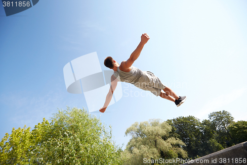 Image of sporty young man jumping in summer park