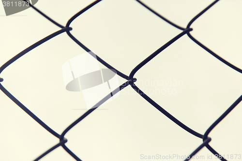 Image of close up of mesh fence over gray sky