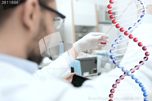 Image of close up of scientist with tube and pipette in lab