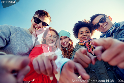 Image of happy teenage friends pointing fingers on street