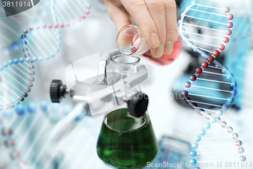 Image of close up of scientist filling test tubes in lab