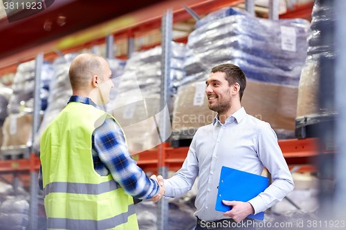 Image of worker and businessmen with clipboard at warehouse