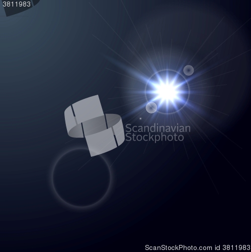 Image of Shiny light lens flare on dark blue background