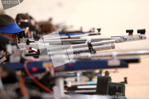 Image of young woman aiming a pneumatic air rifle on sports competition