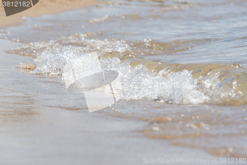 Image of A small sea wave rolls on sandy beach, close-up