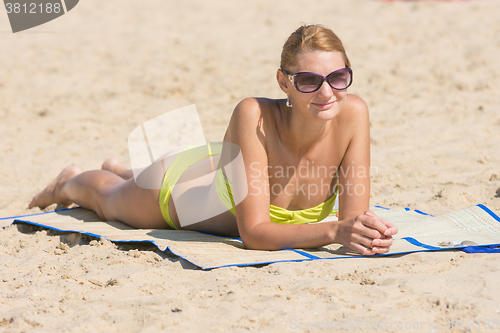 Image of Girl in sunglasses sunbathing on the beach