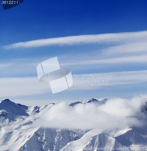 Image of Snow mountains in clouds at sun day