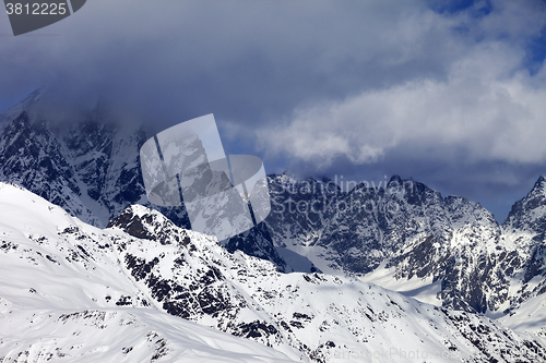 Image of Snowy rocks in clouds at sunny day