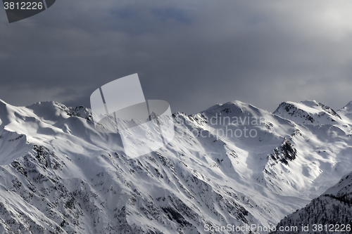 Image of High snowy mountains and sunlight storm sky in evening