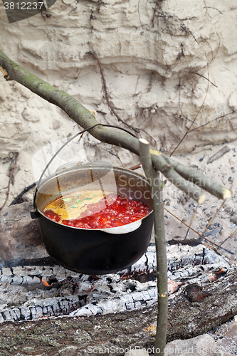 Image of Soup cooking in sooty cauldron on campfire 