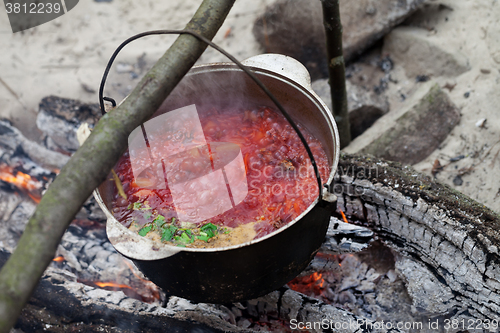 Image of Borscht cooking in sooty cauldron on campfire