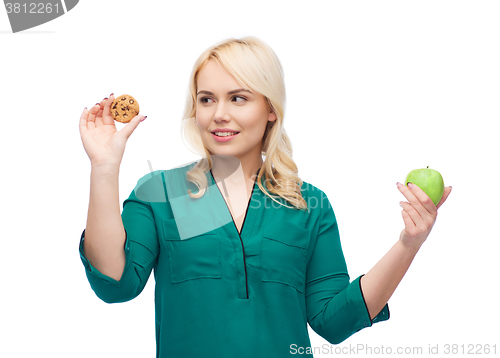 Image of smiling woman choosing between apple and cookie