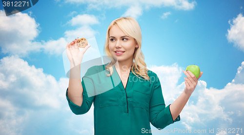 Image of smiling woman choosing between apple and cookie
